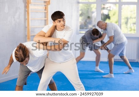 Guy and man fight during training lesson single combat and oriental martial art wrestling class. Men wrestling section, sports club