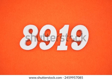 The number 8919 is made from white painted wood placed on a background of orange paper.