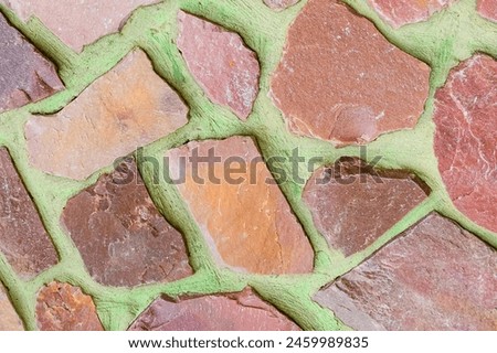 It is photo of colorful stones on green background. Its close up of multicolored stone wall of the building. It is photo of mosaic tile floor. It's view of wall texture.