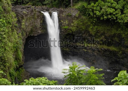 Soft long speed shutter of rainbow waterfall view flowing to the lake with green grass around the cave background