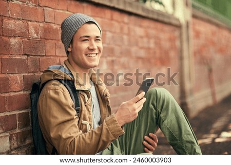 Asian man, cellphone and city travel or brick wall for outdoor tourism in China or texting, communication or smile. Male person, smartphone and location search on mobile app, journey or direction