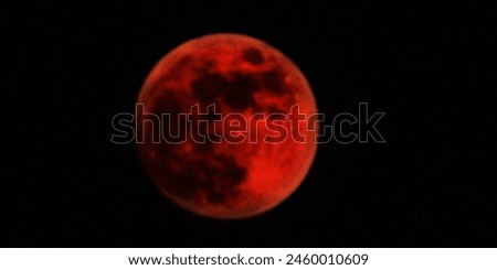 A blurred telescopic image captures the eerie glow of a red moon or an unidentified planet, observed against the dark backdrop of the night sky.

