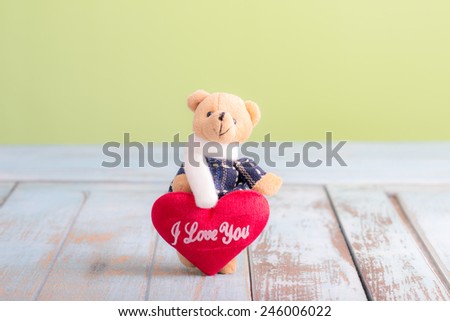 Teddy Bear with red Love heart on wooden table for valentine day