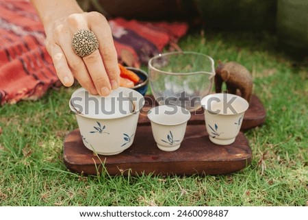 A caucasian woman hosts a Chinese tea ceremony, ceremonial tea set, puer tea, green grass set up, afternoon tea picnic