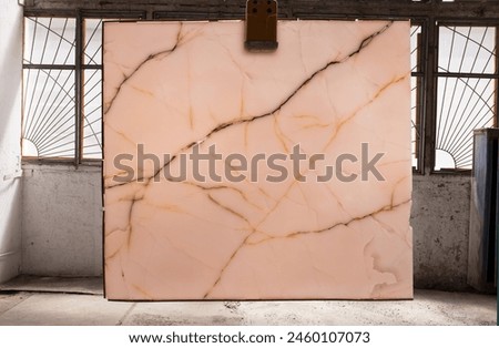 Picture of a marble slab on a hanger, shot in natural light, a cut of decorative marble in a warehouse, a large piece of marble. High Resolution. Backlit Onyx Pink
