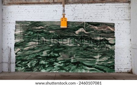 Picture of a marble slab on a hanger, shot in natural light, a cut of decorative marble in a warehouse, a large piece of marble. High Resolution. Marble Verde LAPPONIA