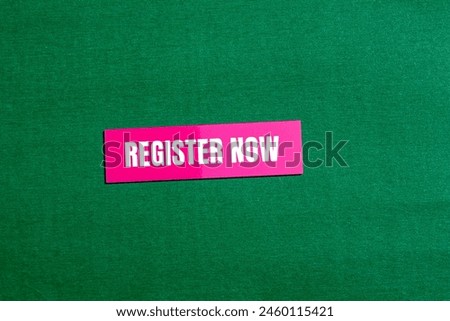 Register now words written on pink paper sticker with green background. Conceptual register now symbol. Copy space.