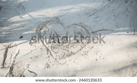 A heart with initials inside is drawn on the white sand of the sea beach. Happy vacation on the sea coast with white soft sand. Drawing on white sand.