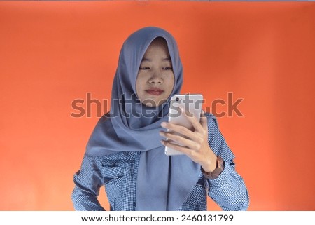 Portrait of an Asian woman making a video call on an orange background