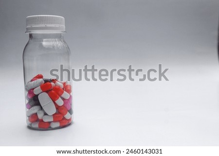 Various kind of medicine pills tablet capsule in a closed plastic bottle white background