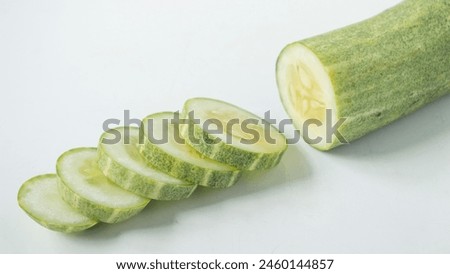 Fresh green cucumbers, cut into pieces, arranged on a white background. Healthy foods and extracts are used as cosmetics to keep facial skin beautiful and moist.