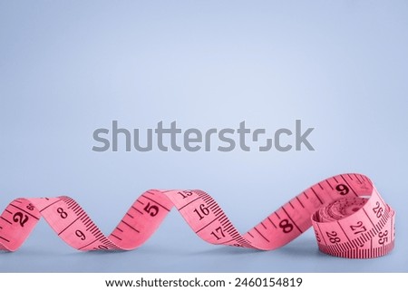 pink ribbon is unwound in a spiral on a blue background, there is room for text Royalty-Free Stock Photo #2460154819