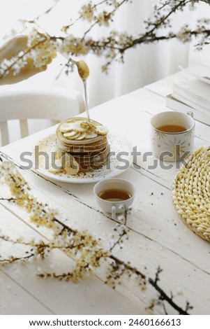 The image is a stack of pancakes drizzled with syrup. It features a dessert served on a table. Tags associated with the image include baked goods, tableware, serveware, snack, and pastry.