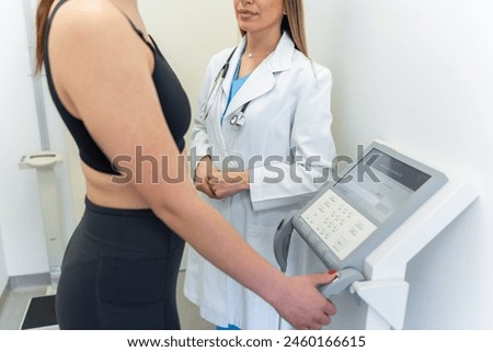 Female doctor measuring patient’s body composition with advanced medical equipment