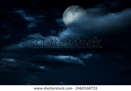 Full moon in night sky with clouds.