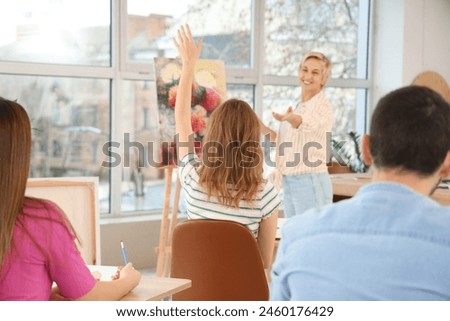 Female art teacher giving lecture to students at school, back view