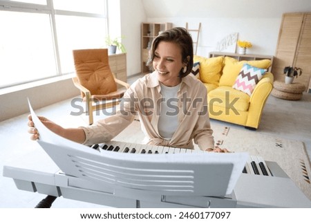 Young woman playing synthesizer at home Royalty-Free Stock Photo #2460177097
