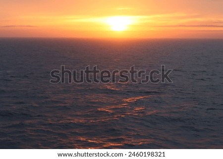Dawn at sea, with waves tinged with golden sunlight Royalty-Free Stock Photo #2460198321