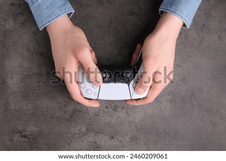 Man using wireless game controller at grey table, top view
