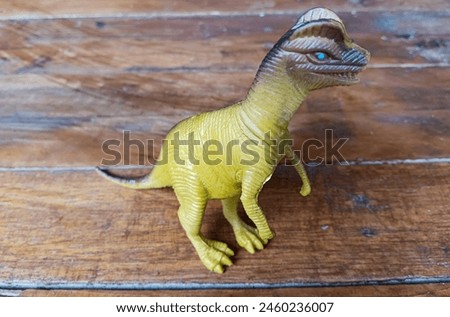 The yellow Tyrannosaurus stands proudly on a wooden board