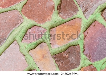 It is photo of colorful stones on green background. Its the close up of multicolored stone wall of building. It is photo of mosaic tile floor. It's view of wall texture.