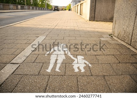 pedestrian zone road sign in Germany, depicting a silhouette of an adult holding the hand of a child, white on a pedestrian zone,
pedestrian sign, woman with child, image on the sidewalk,