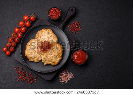 Delicious fried minced chicken cutlets with salt, spices and herbs on a dark concrete background