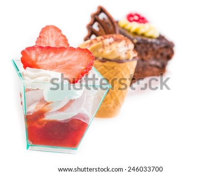 delicious strawberry cake with cream in front of little chocolate and coffee cakes on white background
