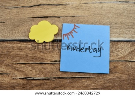 Concept of Kindertag in Language Germany write on sticky notes isolated on Wooden Table.