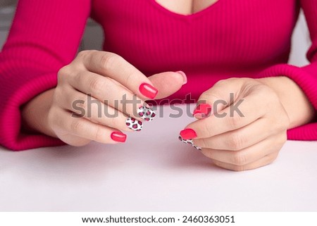 Beautiful female hands with pink manicure nails, leopard print design on white background
