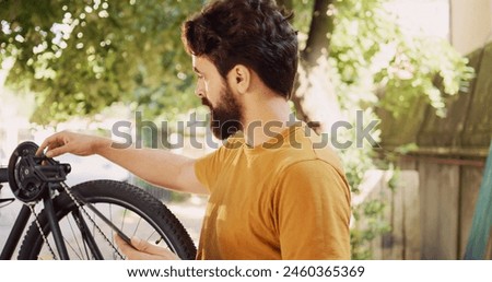Caucasian male cyclist using tablet to browse for equipment and gear to enhance yearly bike maintenance. Determined young man utilizing digital device looking for solutions of damaged bicycle.