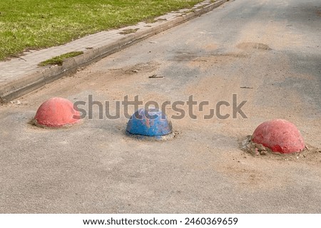 Red and blue restrictive hemispheres on the asphalt road in the parking area of the car and the pedestrian area of walking people at the street. Area for foot people