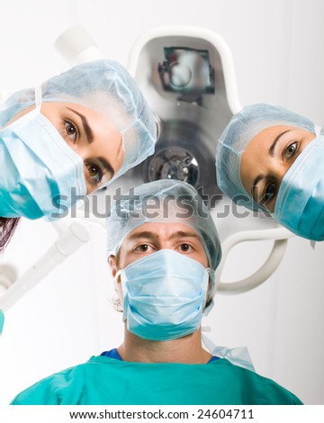 Team of medical professionals looking down at patient in surgical theater
