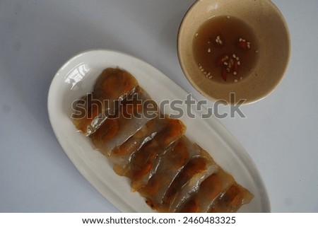 Traditional Banh Loc, a classic dish from Hue, Vietnam, consisting of tapioca dumplings filled with shrimp and pork, served with a tangy fish sauce on a clean white background. Royalty-Free Stock Photo #2460483325