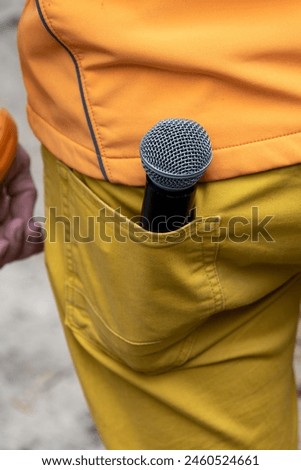 Microphone in the back pocket of yellow trousers, microphone for karaoke, event host, party, singer