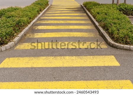 Long yellow pedestrian crossing symbol on the street.