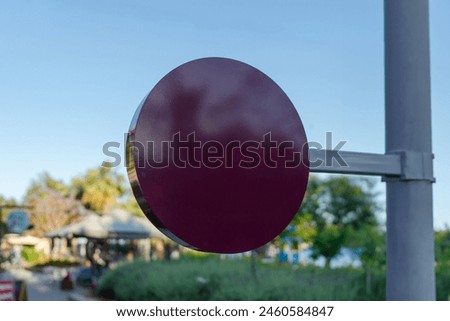 Purple and large empty round store advertising sign, green street background