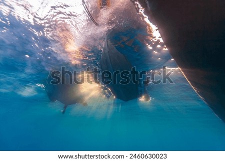 A picturesque view from under the water on the bottom of ships in backlight.