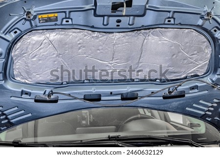 Auto service worker applies soundproof bitumen material to the hood of the car, adjusts the volume of the car or installs sound insulation. Car sound insulation installation process.
