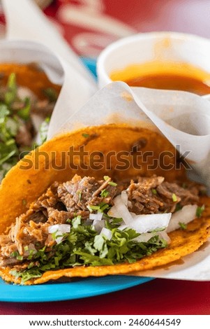 Close up birria taco next to consome. Mexican food