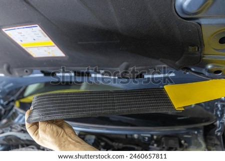 Auto service worker applies soundproof sponge material to the hood of the car, adjusts the sound of the car or installs sound insulation. Car sound insulation installation process.