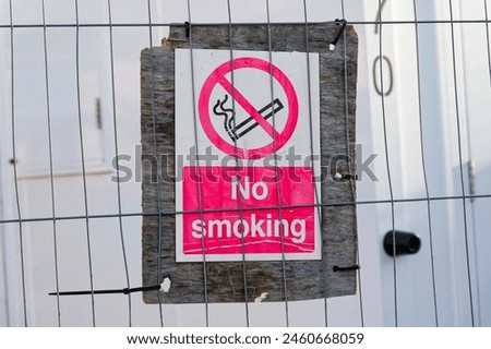 No smoking sign fixed to construction site fence