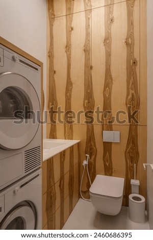 Laundry room with washer, dryer, and toilet fixtures Royalty-Free Stock Photo #2460686395