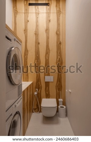 Laundry room with washer, dryer, and toilet fixtures Royalty-Free Stock Photo #2460686403
