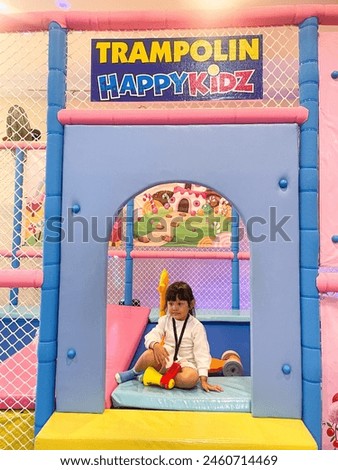 Asian little girl is sitting on a trampoline.