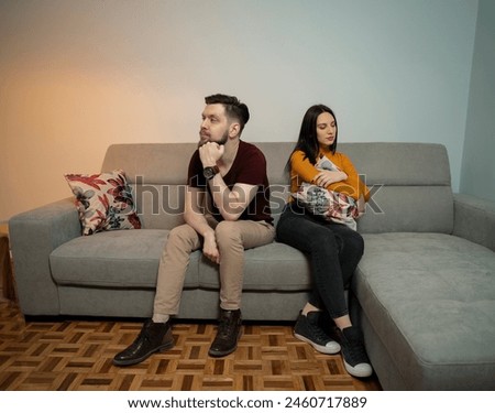 Young heterosexual couple in a fight sitting opposite to each other on couch 