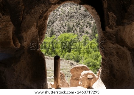 A scenic view out of the entrance way of a cliff dwelling site at Bandelier National Monument in New Mexico. Royalty-Free Stock Photo #2460719293