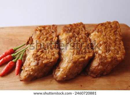 Stock photo of fried tempeh that looks savory with a brownish-yellow color with chili beside it as a meal companion