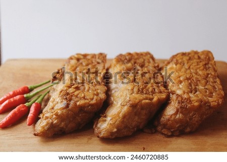 Stock photo of fried tempeh that looks savory with a brownish-yellow color with chili beside it as a meal companion