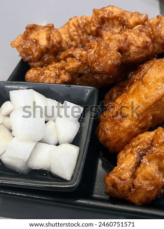 a photography of a tray of food with chicken wings, cubes of sugar and a bowl of.